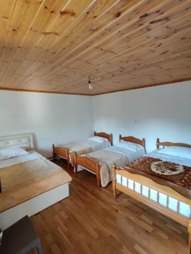 three beds in a room with a wooden ceiling at Guest House Trojani in Lëpushë