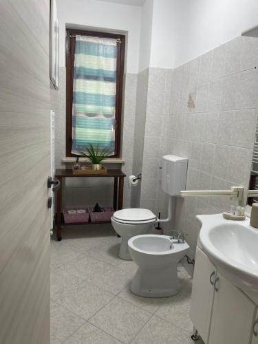 a bathroom with a toilet and a sink and a window at Casa Maya Langhe e Roero in Pocapaglia
