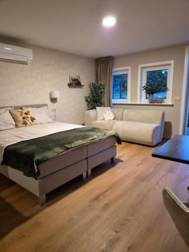 ein Schlafzimmer mit einem großen Bett und einer Couch in der Unterkunft De Brummelstee in Beilen