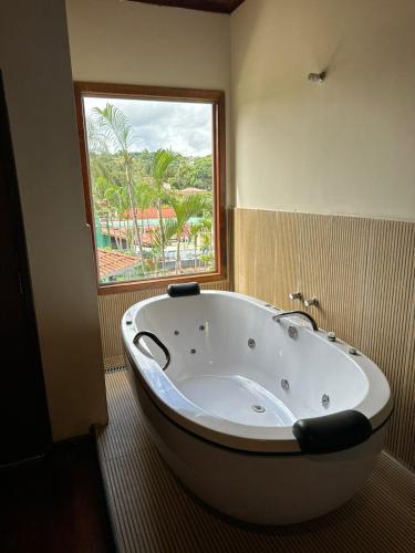 a large bath tub in a bathroom with a window at Hotel Gran Minas in Vespasiano