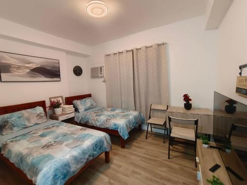 a bedroom with two beds and a desk and a table at Hailey's Place Unit 3 in Bacolod