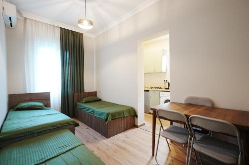 a room with two beds and a desk and a table at Casa Camellia in Kobuleti
