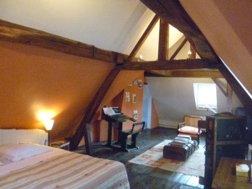um quarto com uma cama e uma secretária num sótão em Chambre d'Hôtes Les Augustins - Parking sécurisé - Borne de recharge em Huy