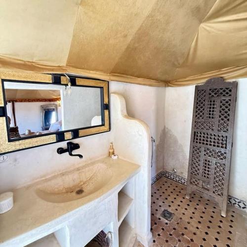 a bathroom with a sink and a mirror at Erg Chigaga Luxury Camp in El Gouera