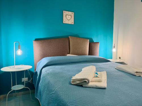 a blue bedroom with a bed with a towel on it at TESEO Siracusa in Ortigia fuori dalla ZTL in Syracuse