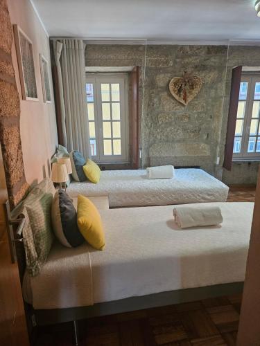 a bedroom with three beds with yellow pillows at Muralha da Barca Apartamentos -Fique no centro do Porto junto a ponte D-Luis IRNAL nº13939 Al,5848 Al, 6419 AL-Chamada para a rede móvel nacional in Porto