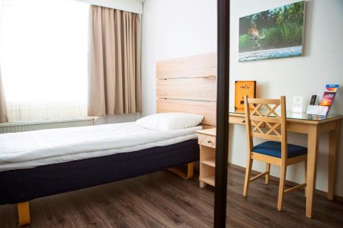 a bedroom with a bed and a desk and a chair at Finlandia Hotel Airport Oulu in Kempele