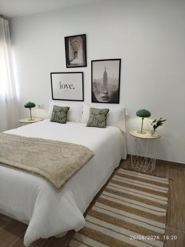 a bedroom with a white bed with a love sign on the wall at Casa do Coto in Islote de Chilreu