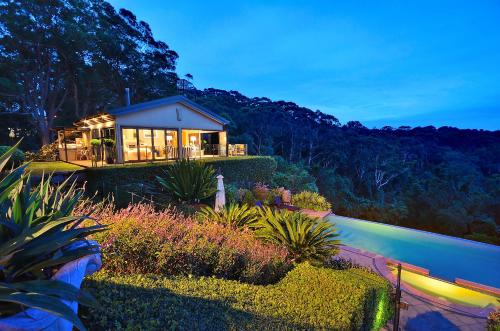 a house with lights on in a garden at night at The Outlook Cabana in Terrigal