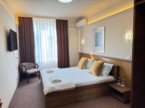 a hotel room with a bed and a chair at Hotel Lux in Mitrovica