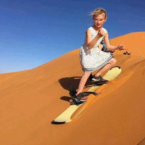 a young girl in a dress riding on a sand dune at Bivouac Camel Trips in Merzouga