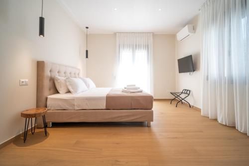 a white bedroom with a bed and a window at Anemi Residence in Chios