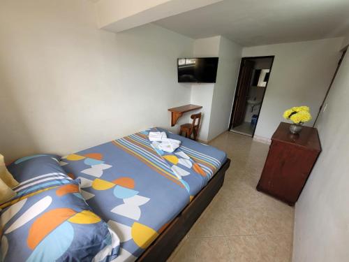 a bedroom with a bed with colorful pillows at Hotel Oriente Real in Rionegro