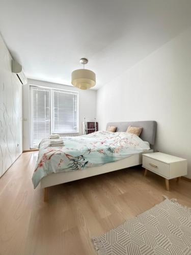 a white bedroom with a bed and a window at GALAXY apartment in Sofia