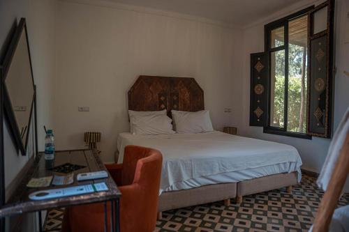 a bedroom with a bed and a table and a chair at Ecolodge Dar bouhouta in Tahannout