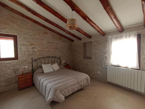 a bedroom with a bed and a stone wall at casa LHort in Benisili