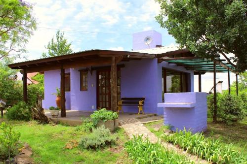 a purple house with a bench in front of it at cabañas aleli in Embalse