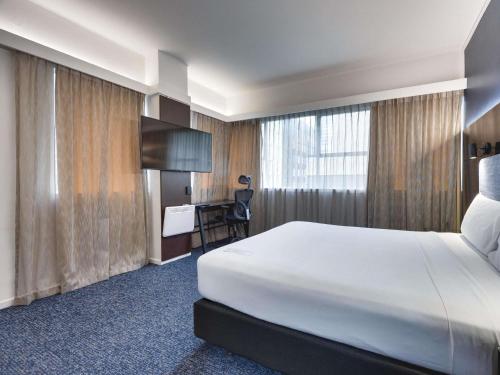 a hotel room with a large bed and a desk at Mercure Wellington Abel Tasman in Wellington