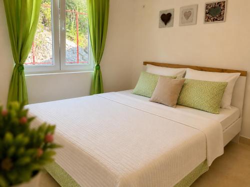 a bedroom with a large white bed with green curtains at CERES APARTMENTS free parking, kitchen & wi-fi in Utjeha