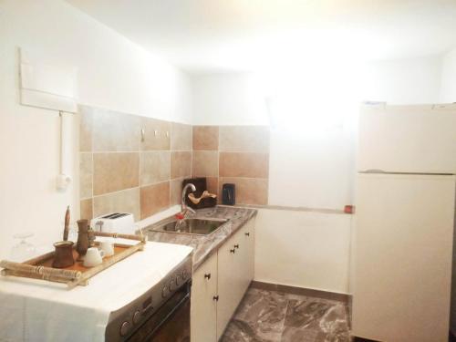 a kitchen with a sink and a white refrigerator at Volcanic Stone Cottage Sea View & Yard in Kipséli