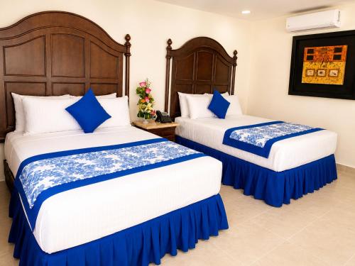 a bedroom with two beds with blue and white sheets at Hotel Catedral Valladolid Yucatan in Valladolid
