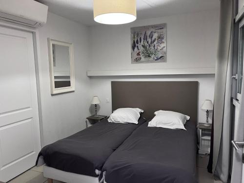 a bedroom with two beds with black sheets and white pillows at Agapanthe in Remoulins