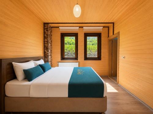 a bedroom with a large bed with two windows at Şimo Suite Otel in Uzungöl