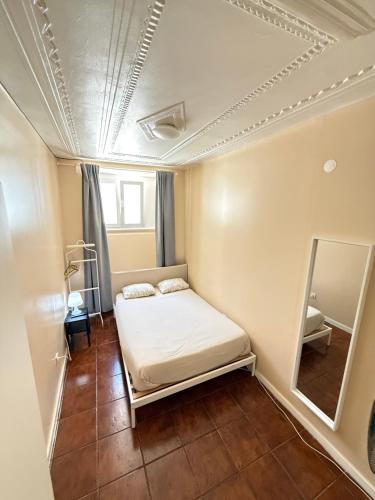 a small bedroom with a bed and a mirror at Lisboa Parque Guest House in Lisbon