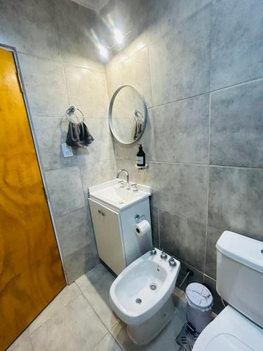 a bathroom with a toilet and a sink and a mirror at Aura Apart in Reconquista