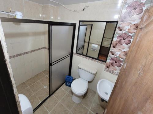 a bathroom with a toilet and two mirrors at Hotel Oriente Real in Rionegro