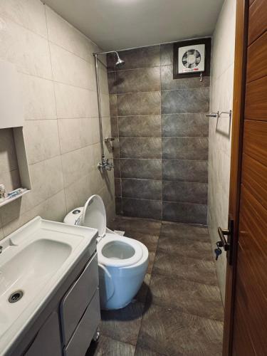 a bathroom with a toilet and a sink at The Margallia in Islamabad