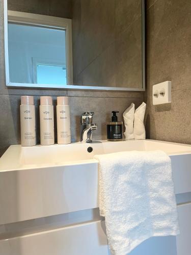 a bathroom with a sink with a mirror and towels at Brightside Suite in Kristiansand