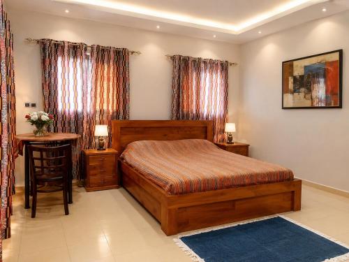 a bedroom with a bed and a table and curtains at JONARIC Residence - Luxury Villa in Lomé in Azyagbang