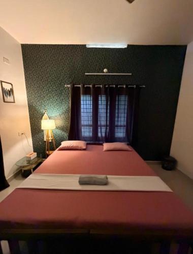 a bedroom with a red bed with a window at Villa mud apples varkala in Varkala