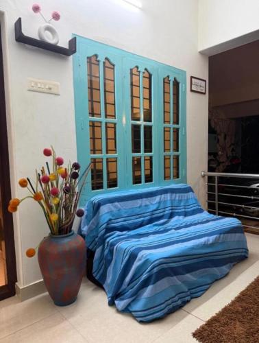 a bed with a blue headboard and a vase with flowers at Villa mud apples varkala in Varkala