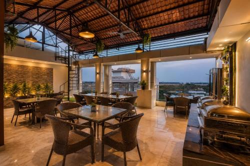 a restaurant with tables and chairs and large windows at Hotel Vibe BLU & Banquet Near Advant, Embassy Oxygen & Sector 142,143 Metro, Noida in Noida
