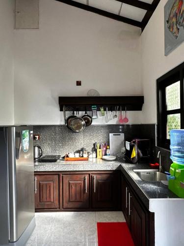 a kitchen with wooden cabinets and a stainless steel refrigerator at Sunbeam Villa in Tangalle