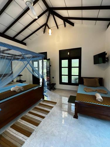 a room with two beds and a television in it at Sunbeam Villa in Tangalle