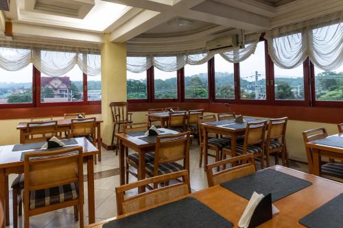 a restaurant with tables and chairs and windows at HANNA Pórtico Hotel - Gramado in Gramado