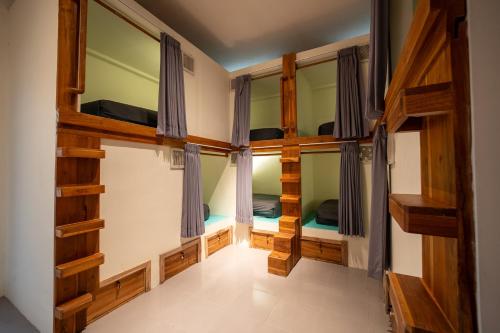 a room with four bunk beds and windows at The Purple Pineapple Beach Hostel in Kuta Lombok