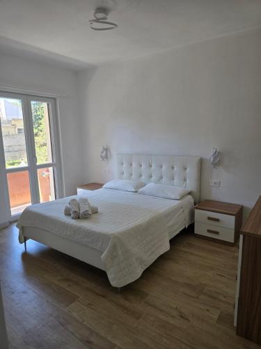 a white bedroom with a large bed and a window at Guest House Tra Rocce E Mare in La Maddalena