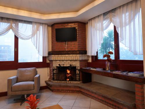 a living room with a fireplace and a television at HANNA Pórtico Hotel - Gramado in Gramado