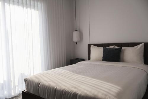 ein Schlafzimmer mit einem Bett mit weißer Bettwäsche und einem Fenster in der Unterkunft Hotelia in Saint-Ambroise