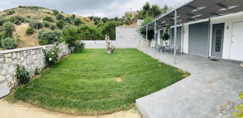 a backyard of a house with a grass yard at Argo Summer Apartment in Agioi Apostoli