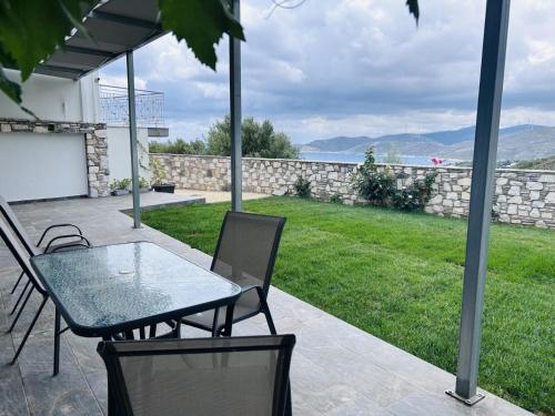 a patio with a table and chairs and a yard at Argo Summer Apartment in Agioi Apostoli