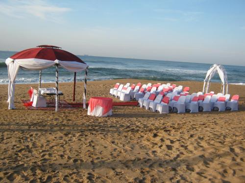 a row of tables and an umbrella on a beach at La Mercy Beach Hotel in La Mercy