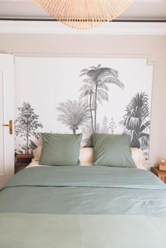 a bed with green sheets and palm trees on the wall at Quartier hippodrome in Cagnes-sur-Mer