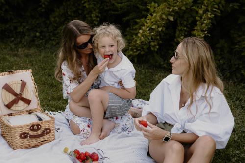 two women and a little girl eating fruit on a blanket at Końska Dolina in Krynica Zdrój