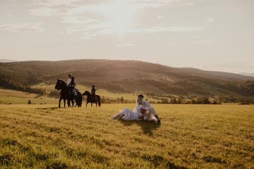 a group of people riding horses in a field at Końska Dolina in Krynica Zdrój