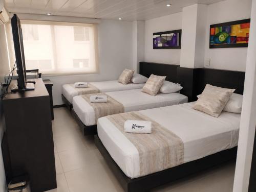 a hotel room with three beds and a television at Hotel Metropolitano in Neiva